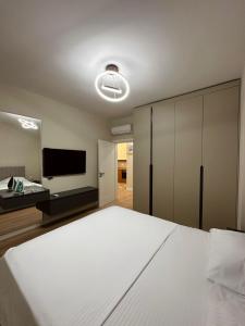 Schlafzimmer mit einem großen weißen Bett und einem Flachbild-TV in der Unterkunft 3H apartment ,Vienna Residence in Shkodra