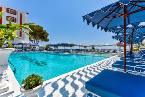 a swimming pool with blue chairs and an umbrella at Hotel Mongibello Ibiza in Santa Eularia des Riu