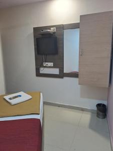 Habitación con cama y TV en la pared. en Hotel Gitanjali en Ahmedabad