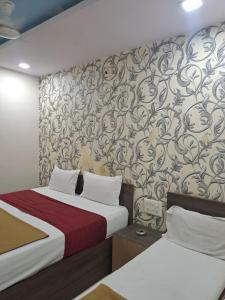 a bedroom with two beds and a wall with a wallpaper at Hotel Gitanjali in Ahmedabad