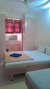 a bedroom with two beds and a window with red curtains at Hotel Gitanjali in Ahmedabad