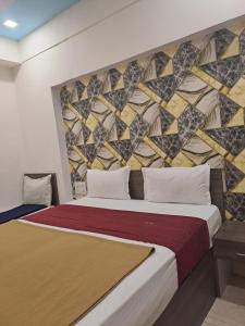 a bedroom with a large bed with a wall with a mural at Hotel Gitanjali in Ahmedabad