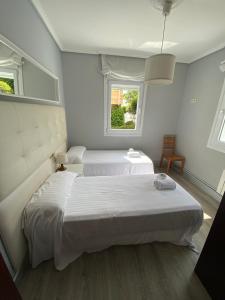 a white bedroom with two beds and a window at Chalet Rialeda in Oleiros