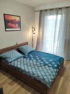 um quarto com uma cama com um edredão azul e uma janela em STARA CEGIELNIA, Faktura VAT, bezkontaktowe zameldowanie em Poznań