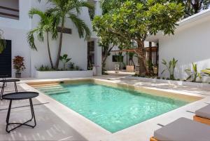 a swimming pool in the middle of a yard with trees at Aalada Playa del Carmen in Playa del Carmen