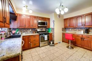 una cocina con armarios de madera y una silla roja. en Spacious Pittsburgh Rental Walk to Frick Park! en Pittsburgh