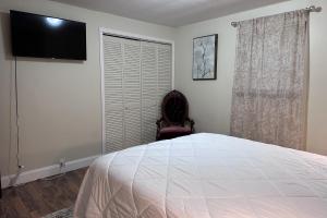 1 dormitorio con 1 cama, 1 silla y TV de pantalla plana en Tennessee Harmony, en Sevierville