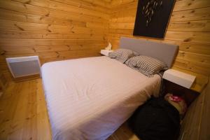 ein Schlafzimmer mit einem weißen Bett an einer Holzwand in der Unterkunft Cottage autour de l'étang 80 in Bourbourg