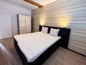 um quarto com uma cama grande com lençóis brancos e almofadas em B&B aan de Markt em Roermond