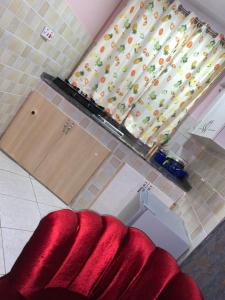 a living room with a red couch and a window at Thee Haven 3 in Kampala +6 photos