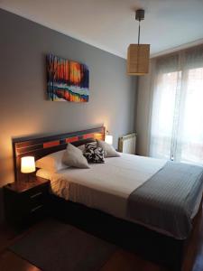 ein Schlafzimmer mit einem großen Bett mit einer weißen Tagesdecke in der Unterkunft Apartamento Galería Gijón in Gijón