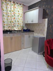 a kitchen with white cabinets and a red chair at Thee Haven 3 in Kampala