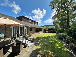 uma casa com um quintal com cadeiras e um guarda-sol em 'Sounion' - Fabulous, spacious modern house with large private garden in Leafy Lytham em Lytham St Annes