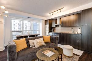 a living room with a couch and a kitchen at 3BR Rooftop Pool Gym Steps to MTCC and CN Tower with Parking in Toronto