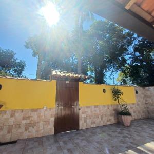 a yellow wall with a wooden door and a plant at Suítes Estou de Férias Paraty in Paraty