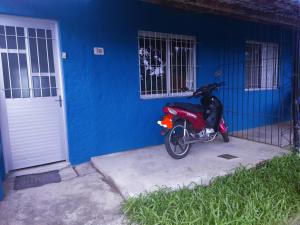 una motocicleta roja estacionada frente a un edificio azul en Alojamiento Carol, en Melo