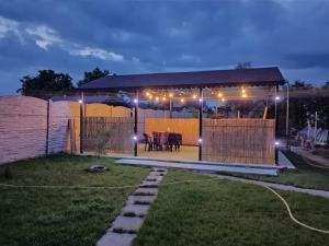 - un kiosque avec une table dans la cour la nuit dans l'établissement Camera de la Bunici - o poarta catre oriunde, à Secuiu