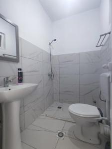 a white bathroom with a toilet and a sink at ROLEO Guest House in Lin