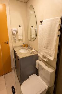ein Badezimmer mit einem WC, einem Waschbecken und einem Spiegel in der Unterkunft Studio Savana in São Paulo