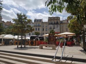 a park with tables and umbrellas in a city at Agate, clim, lumière et cachet. in Béziers