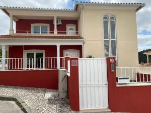 a red and white house with a white fence at Amazing Scorpion´s House Leiria in Leiria