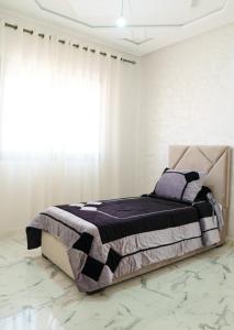 a bed in a white room with a large window at Ayour appartement in Azrou