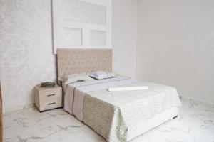 biała sypialnia z łóżkiem i stolikiem nocnym w obiekcie Ayour appartement w mieście Azrou