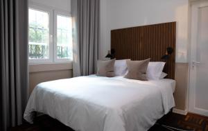 um quarto com uma grande cama branca e 2 janelas em Fausto em Lima