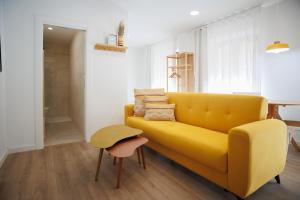 a living room with a yellow couch and a stool at KS Tiendas 8 in Almería