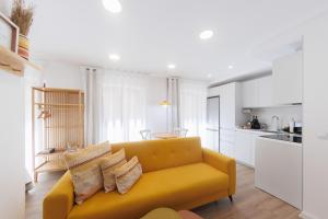 a living room with a yellow couch and a kitchen at KS Tiendas 8 in Almería