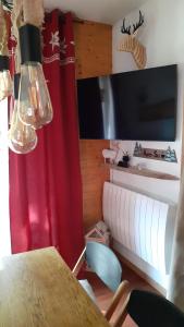 a dining room with a table and a red curtain at VALFREJUS - Appartement "L'Erable" Les Chalets de Florence 2 - Chaleureux et fonctionnel - plein centre à côté des télécabines - 4 à 7 pers in Valfréjus
