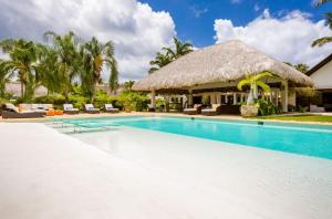 - une piscine dans un complexe avec toit de chaume dans l'établissement Sunny Vacation Villa No 57, à San Rafael del Yuma