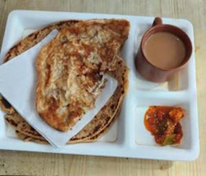 a plate of food with pancakes and a cup of coffee at Hotel Sai Guest House, Jadavpur kolkata in Kolkata