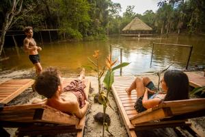 un grupo de niños sentados en bancos cerca de un cuerpo de agua en AWAKEN Amazonian Healing Resort ALL INCLUSIVE, en Iquitos