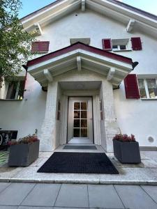 a front door of a white house with two plants at Sottotetto grazioso St.Moritz in St. Moritz