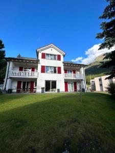 サンモリッツにあるSottotetto grazioso St.Moritzの赤いドアと緑の庭がある大きな白い家