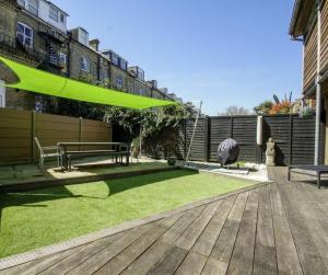 um jardim com um deque de madeira e um guarda-sol verde em THE EDGE - Architect Designed - by Crown Gardens Holiday Homes em Brighton & Hove