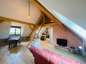 a living room with a couch and a tv in a attic at Studio à la ferme 