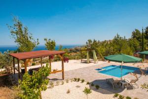 a patio with a pool and umbrellas at Villa Paradiso Sunset in Pomos