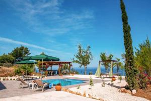 una piscina con sillas y sombrillas y el océano en Villa Paradiso Sunset, en Pomos
