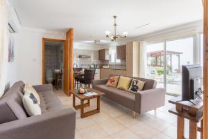 a living room with two couches and a tv at Villa Paradiso Sunset in Pomos