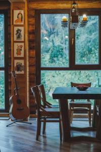 uma sala de jantar com uma mesa e uma guitarra numa cabana em Sabay Sai Wooden Guesthouse in The National Park em Almaty