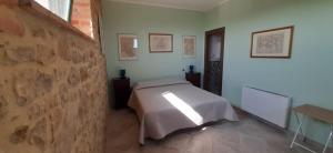 1 dormitorio con cama y pared de piedra en Agriturismo Il Sassolino, en Ripalvella