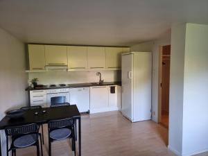 a kitchen with white cabinets and a black table and chairs at Apartment 7 min from the airport in Bergen