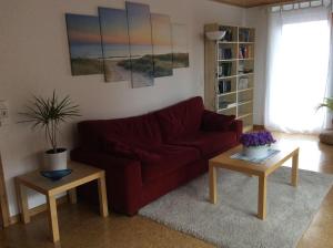 ein Wohnzimmer mit einem roten Sofa und 2 Tischen in der Unterkunft Ferienwohnung Lösch in Neuenburg am Rhein