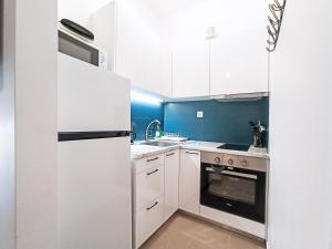 małą kuchnię z białymi urządzeniami i niebieskimi ścianami w obiekcie Kremou Studio w Atenach