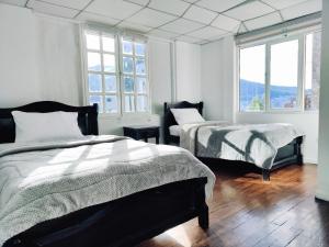 a bedroom with two beds and two windows at Hotel Muros Quito in Quito