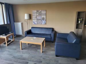 Sala de estar con 2 sofás azules y mesa de centro en Het Pareltje, en Brouwershaven