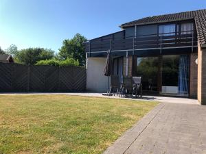 a house with a patio with an umbrella and a lawn at Het Pareltje in Brouwershaven