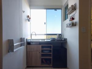 uma pequena cozinha com um lavatório e uma janela em Suíte e copa com vista - Di Roma Rio Quente em Rio Quente